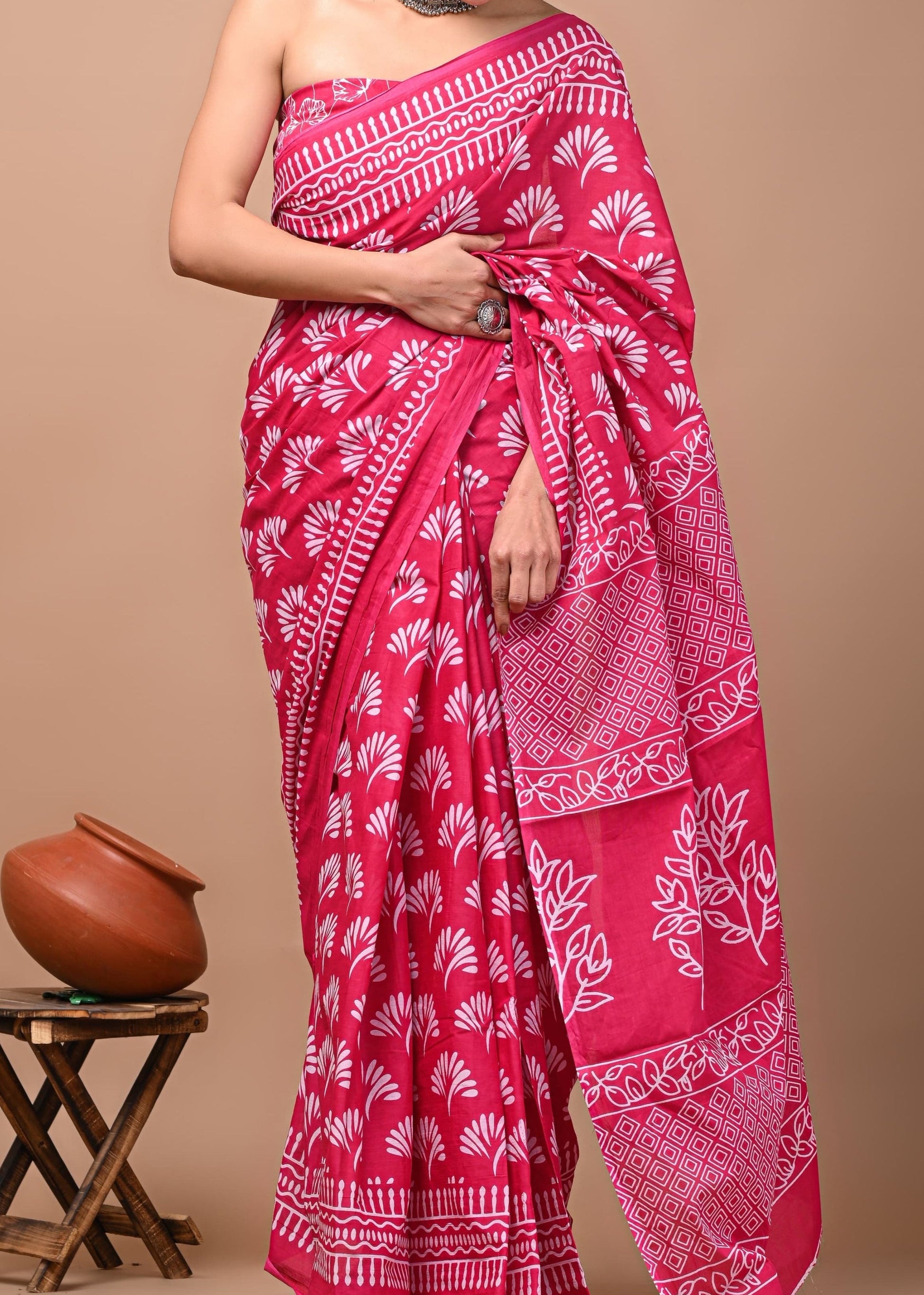 Woman wearing a pink saree with white patterns on a beige background